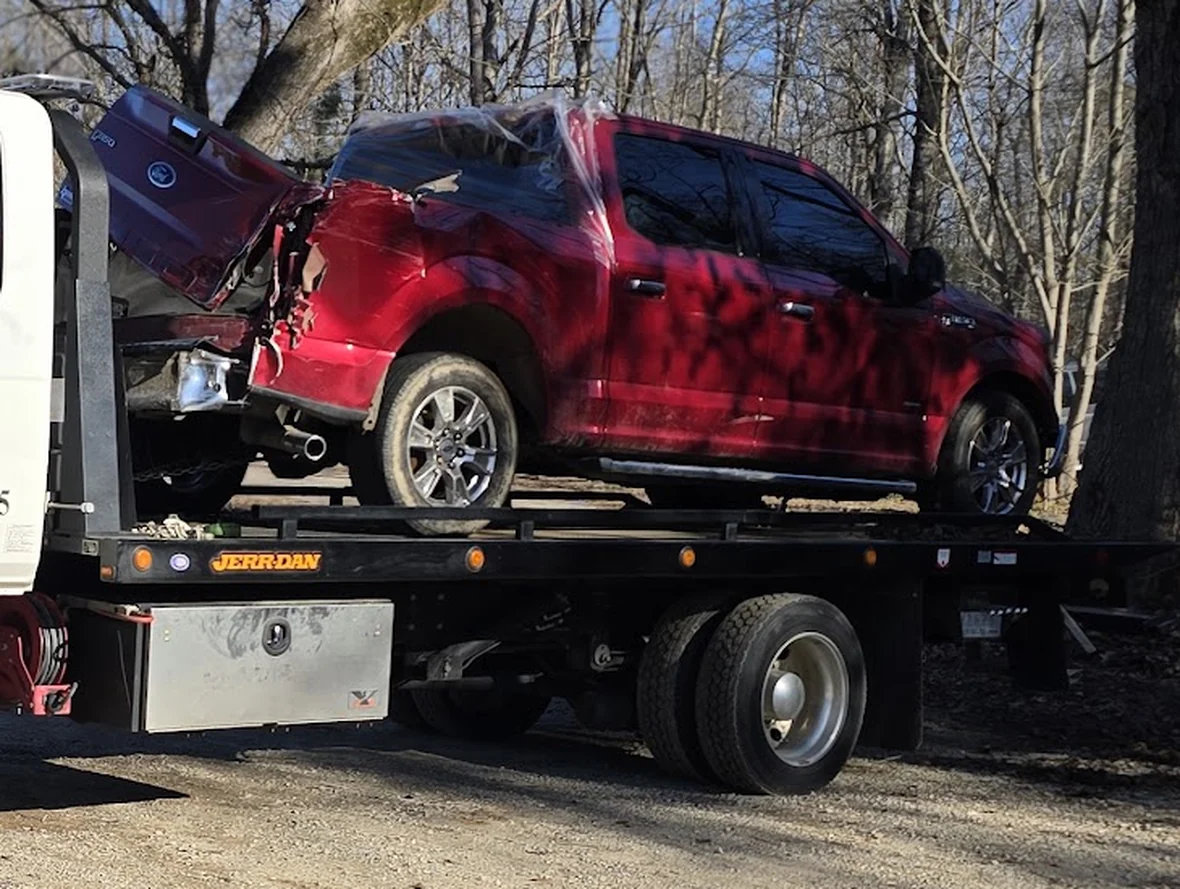 A collision-damaged pickup loaded and secured on the Jerr-Dan flatbed deck
